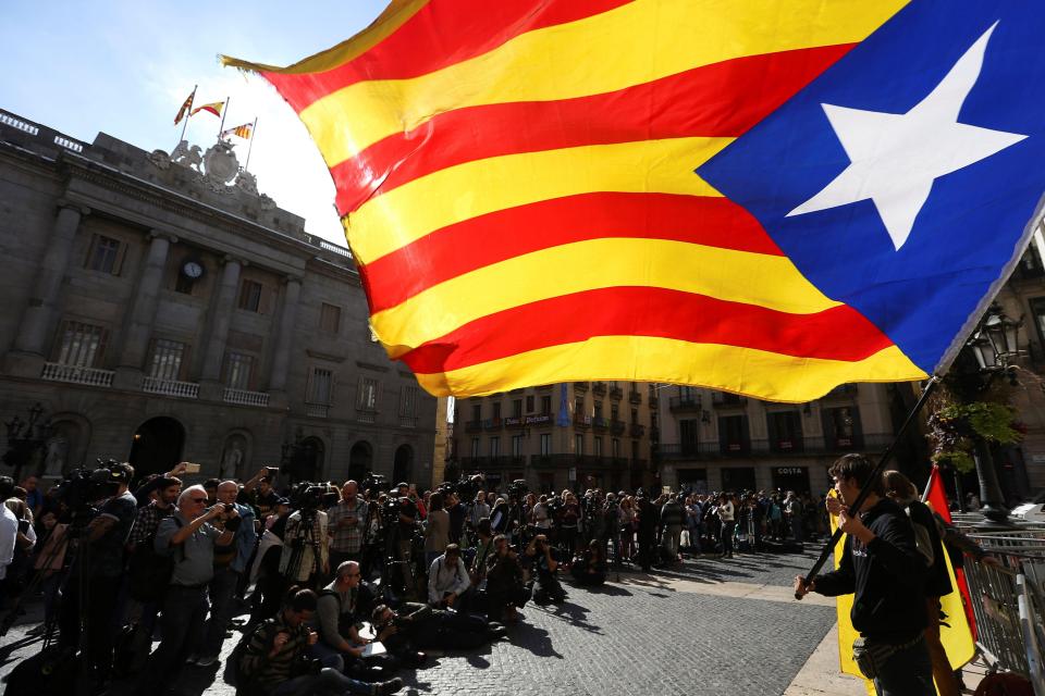  A pro-independence demonstrator waves the Catalan flag outside the regional government offices, as Mr Puidgemont was threatened with arrest if he turned up for work