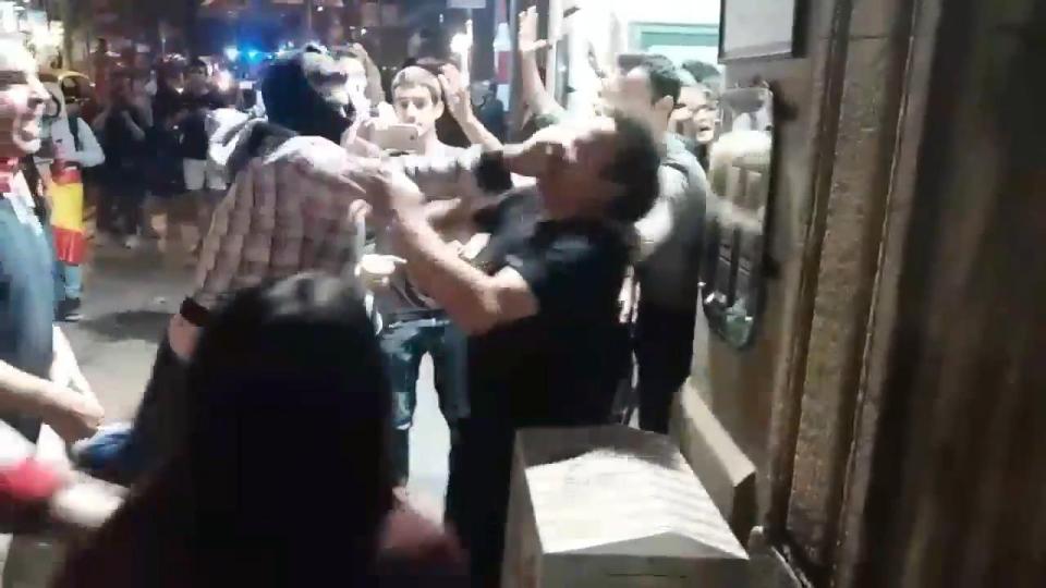 A masked Catalan independence supporter punches a man amid violent scenes in Barcelona last night