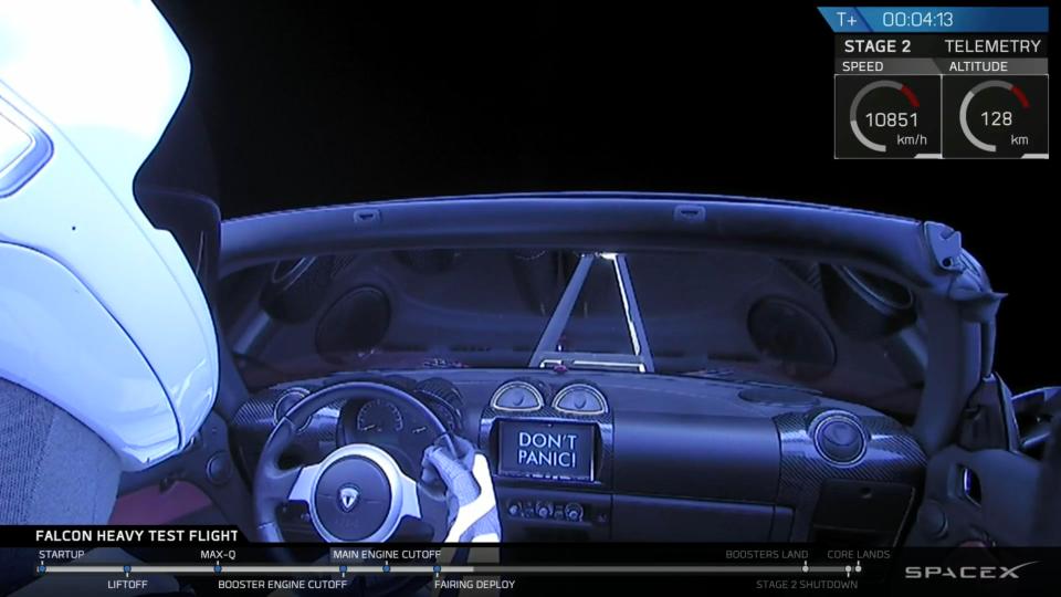  A dummy sits in the driver's seat of Elon Musk's Mars-bound sports car, the 'Don't Panic' sign visible on the dashboard