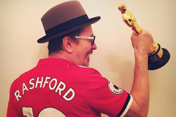 Gary Oldman poses with his Oscar wearing a signed Marcus Rashford shirt