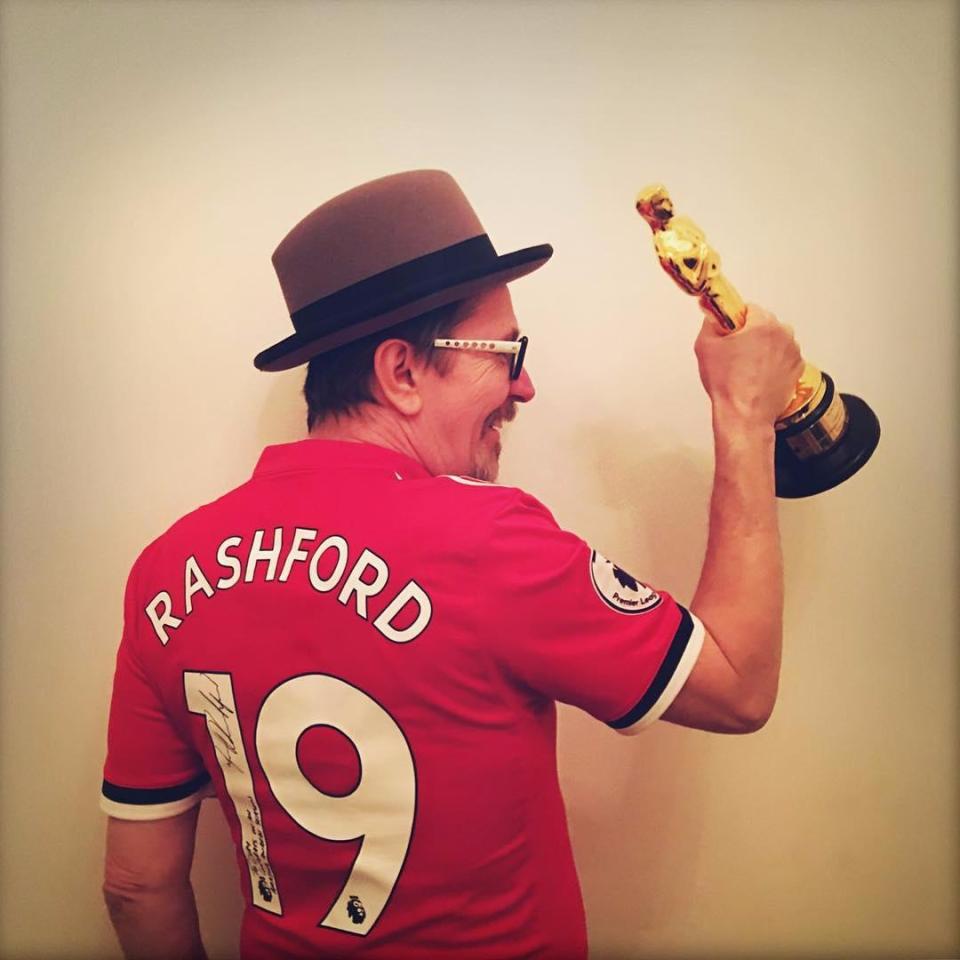 Gary Oldman poses with his Oscar wearing a signed Marcus Rashford shirt