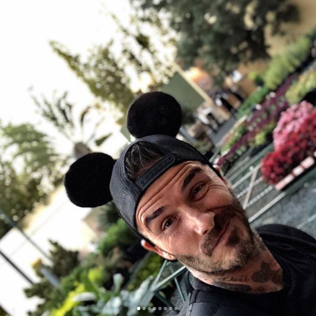  The former footballer looks relaxed in a black Mickey Mouse cap and matching T-Shirt
