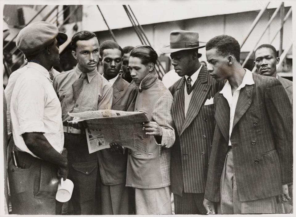  New arrivals reading a newspaper while waiting to get off the ship