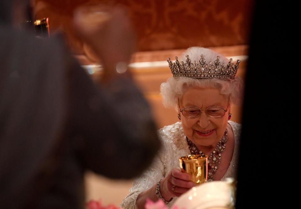  The Queen beams as she picks up a golden cup at the palace dinner