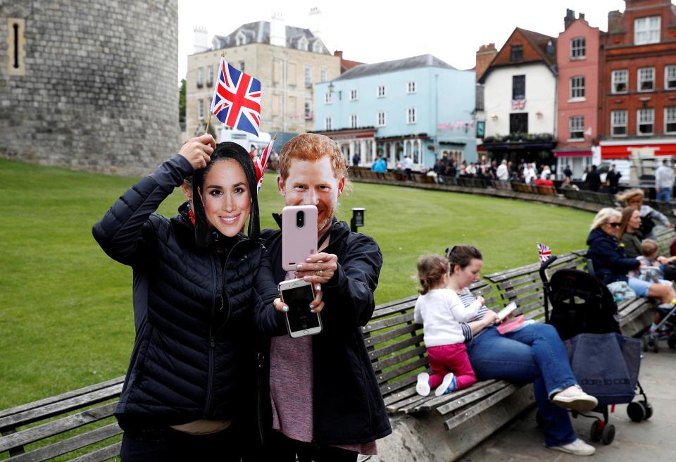 Two people pose with Harry and Meghan masks