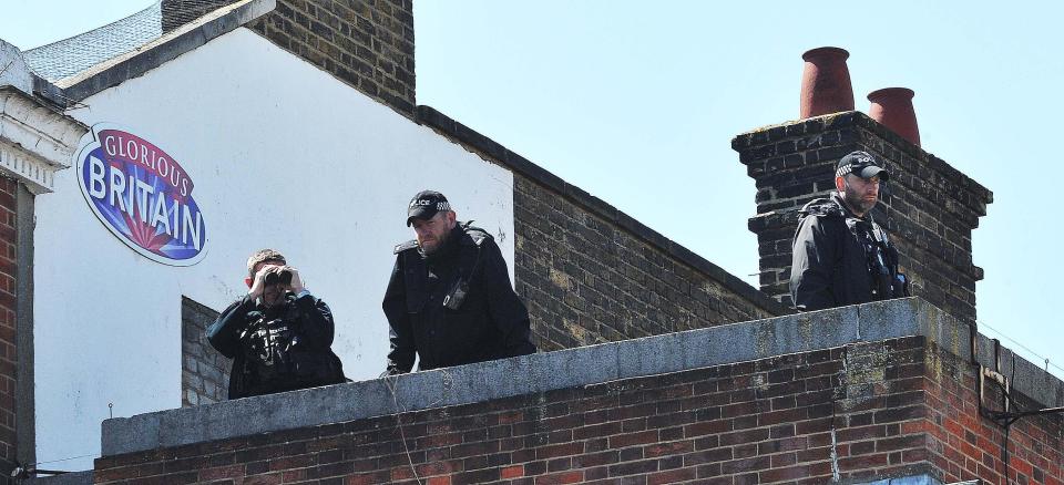 An officer peers at crowds through binoculars ahead of the wedding of the year
