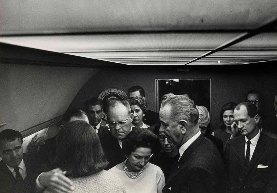 Jackie is seen being comforted by those in the small room aboard the plane 