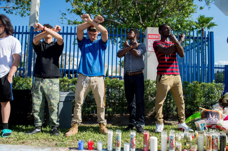  A group stand with their arms crossed in Xs to pay tribute to the rapper, who went by the stage name XXXTentacion