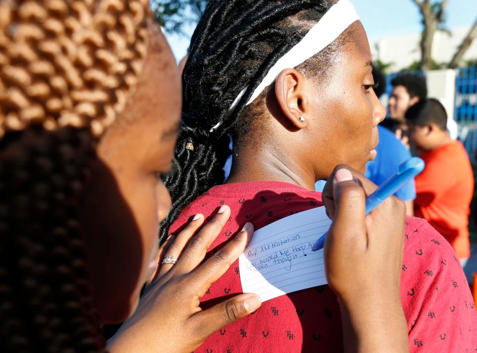  A woman leans on a friend to write out a heart felt message in tribute to the star