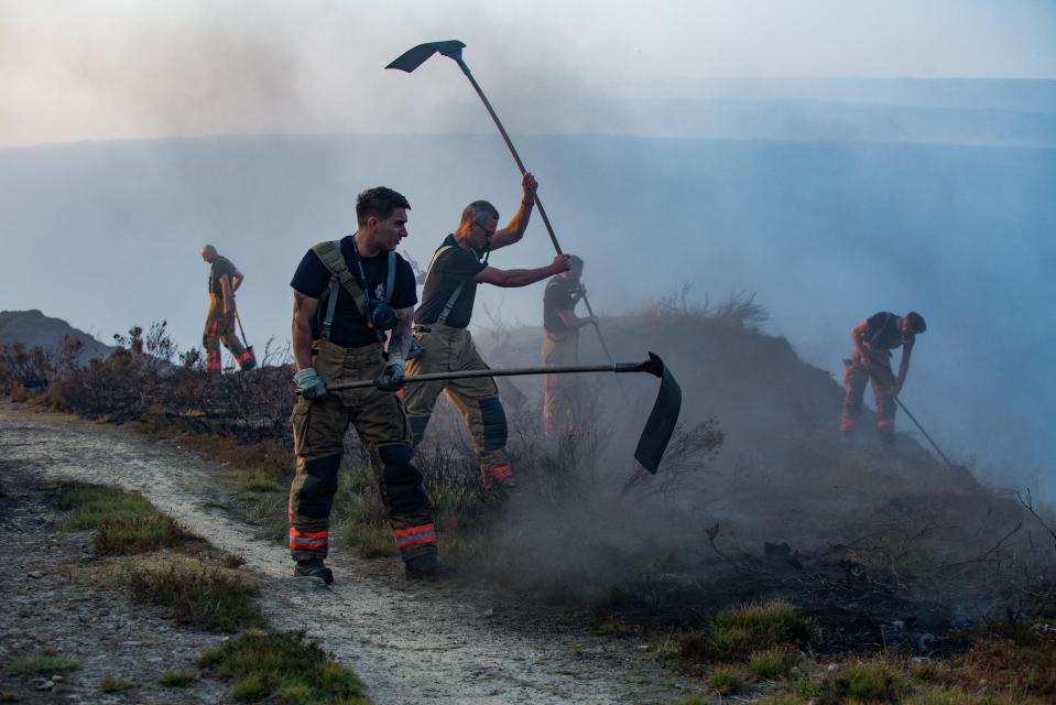  Firefighters attempt to put out the smouldering ground above Manchester