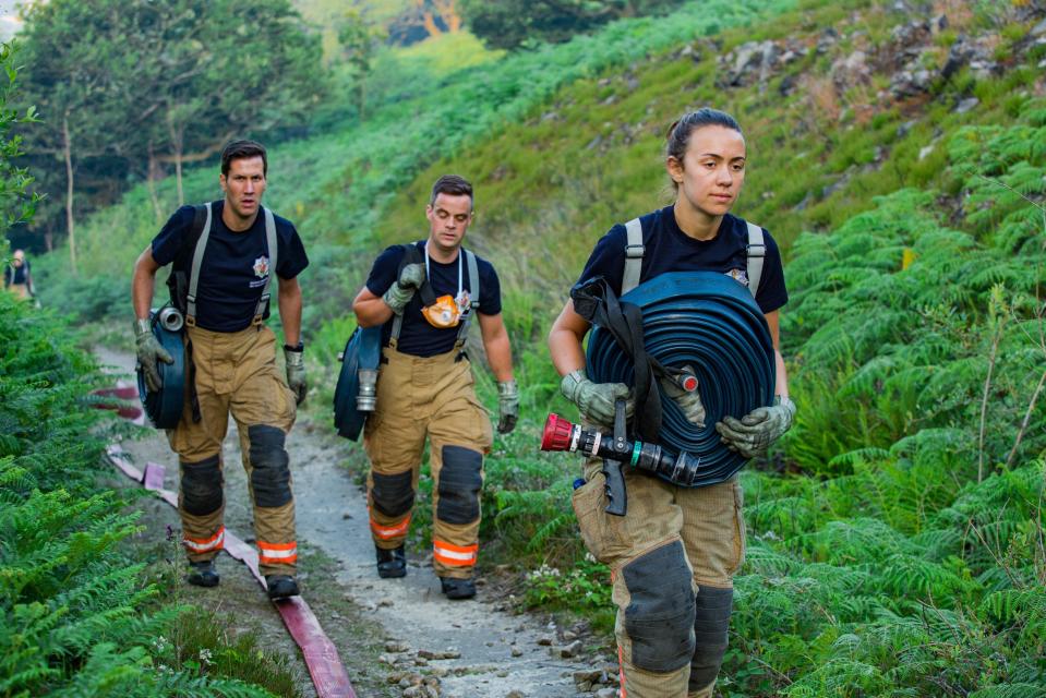  Firefighters carry their hoses towards the blaze on moorland
