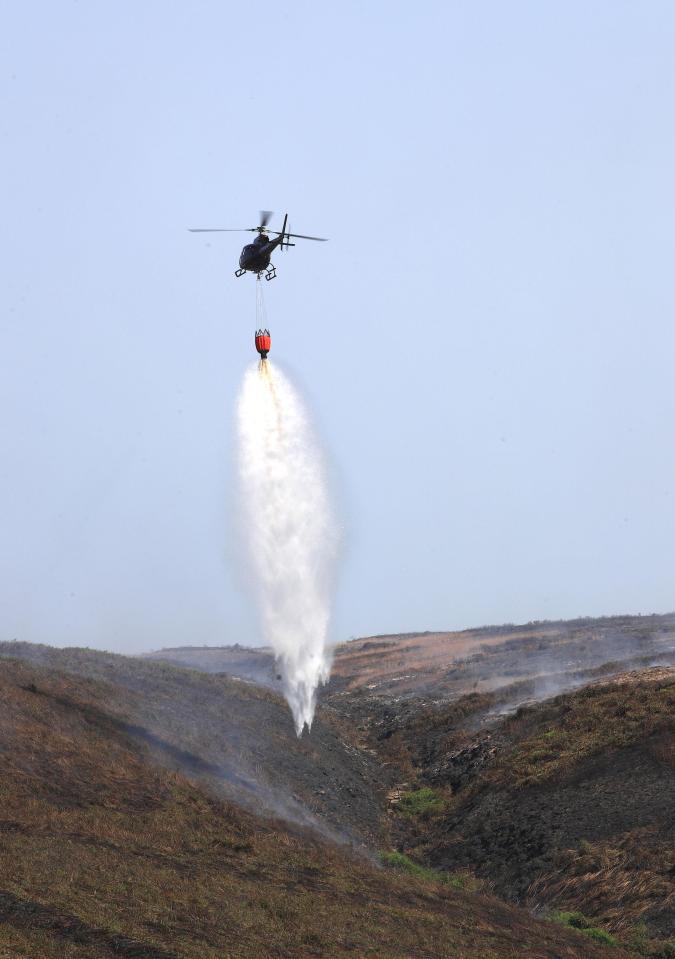  A helicopter dumps water on Saddleworth Moor in a bid to extinguish the flames