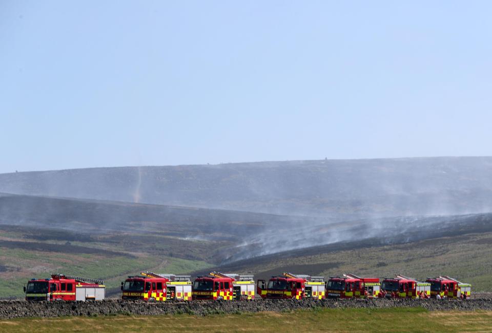  Fire appliances line up behind each other as the blaze continues in the distance