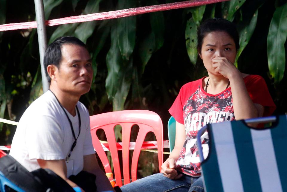 Family members sit in tent near the cave entrance, waiting for news of their children and the coach