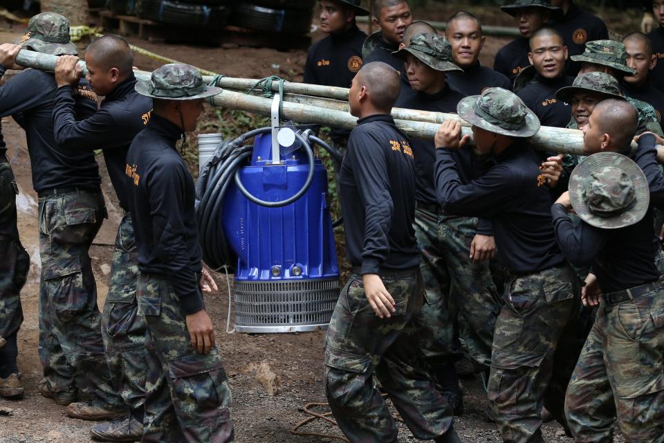  Thai soldiers carry a pump to the cave as rescuers try to keep the water levels low