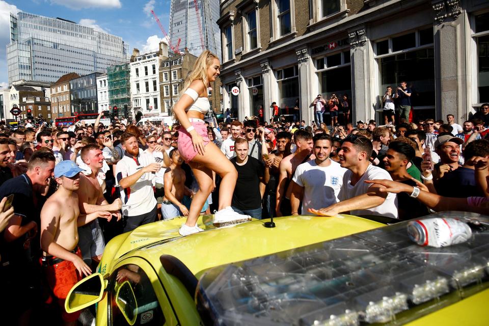  A woman was filmed standing on top of an ambulance car as a crowd cheered around her