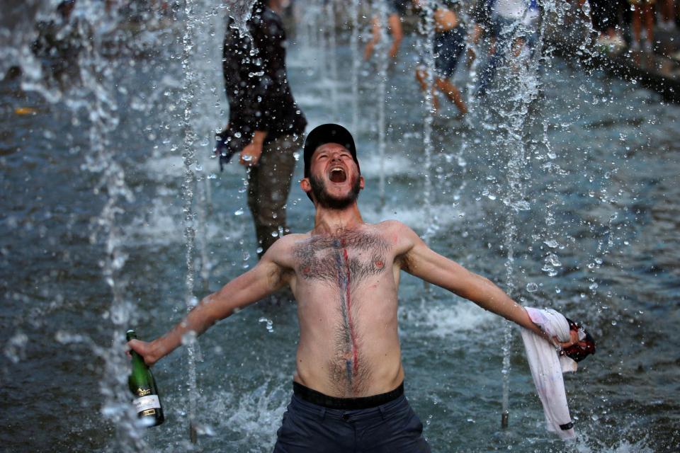 A France supporter celebrates with bubbly and his shirt off after beating Croatia
