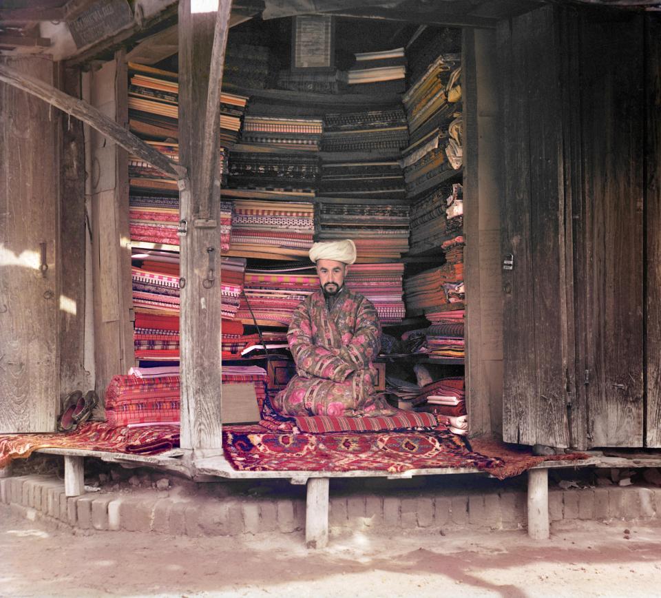  A merchant at a Samarkand market with displays of silks, cotton, and wool fabrics in Uzbekistan