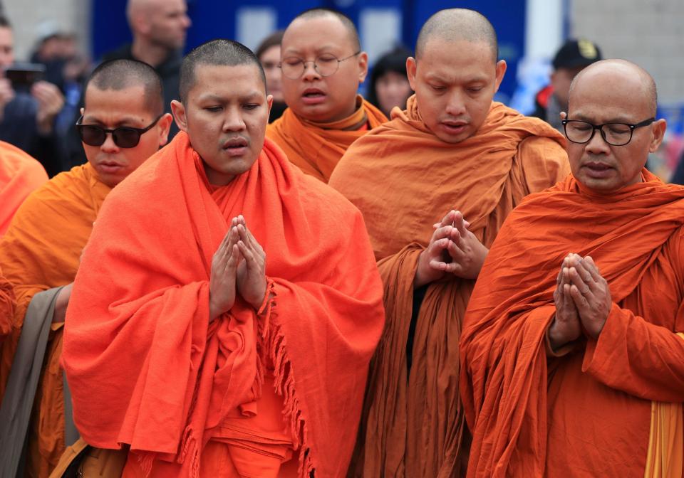 Monks pray near the memorial for the Leicester City owner