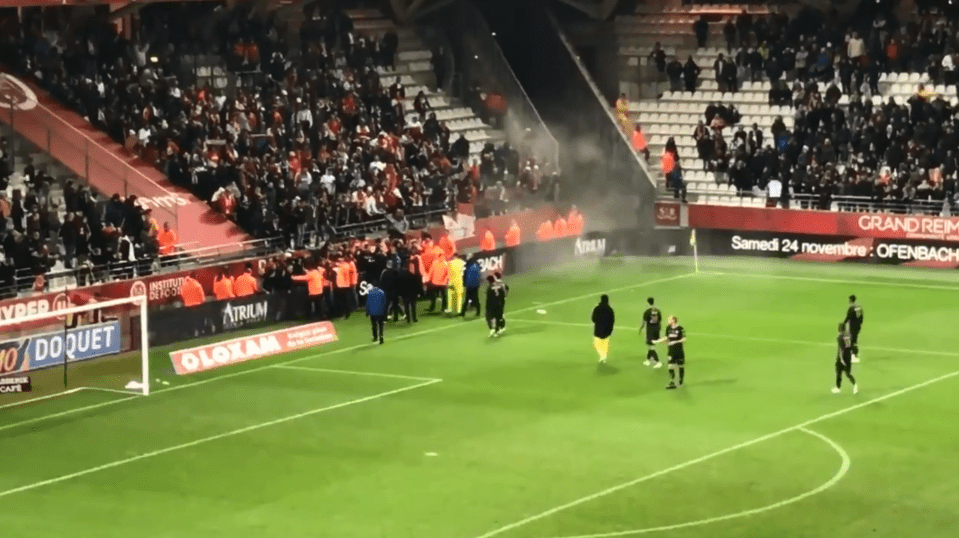 Stewards were forced to hold the angry spectators back as a flare appeared to be set off