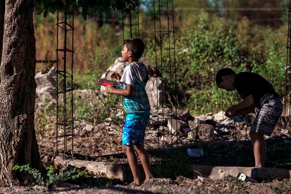 A boy plays with a toy gun near the crime scene where a man was shot dead in Culiacan, Sinaloa state, Mexico, where El Chapo's cartel still rules the roost 