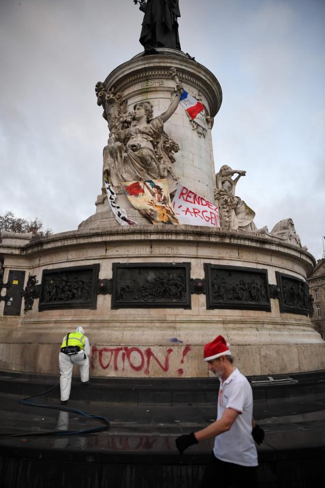  A man walks past a sign reading 'Give the money back' onPlace de la Republique in Paris, December 9