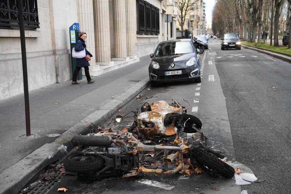  A woman walks past burnt scooters on quai d'Orsay in Paris, on December 9