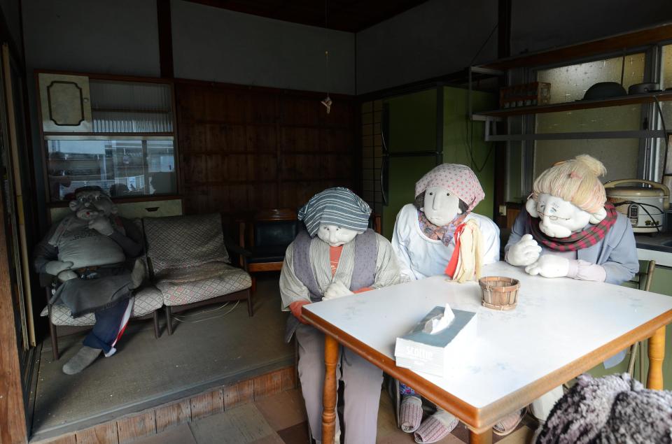  Three elderly looking dolls sit around the kitchen table while another doll lounges on the sofa with his legs crossed