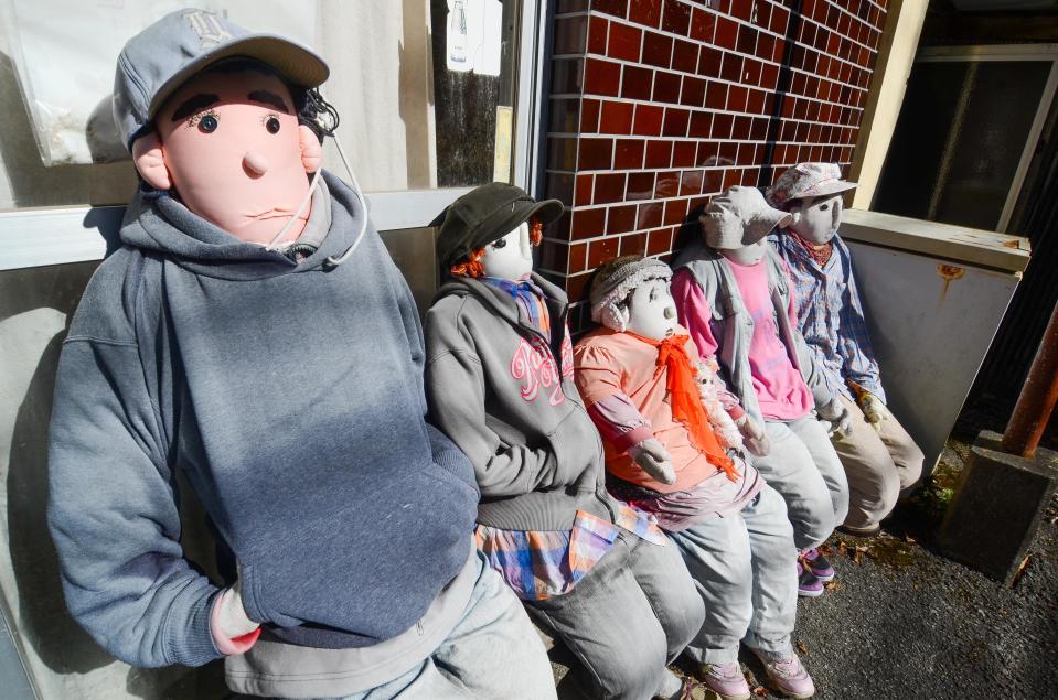  A group of dolls soak up the sun as they sit beneath a bus shelter