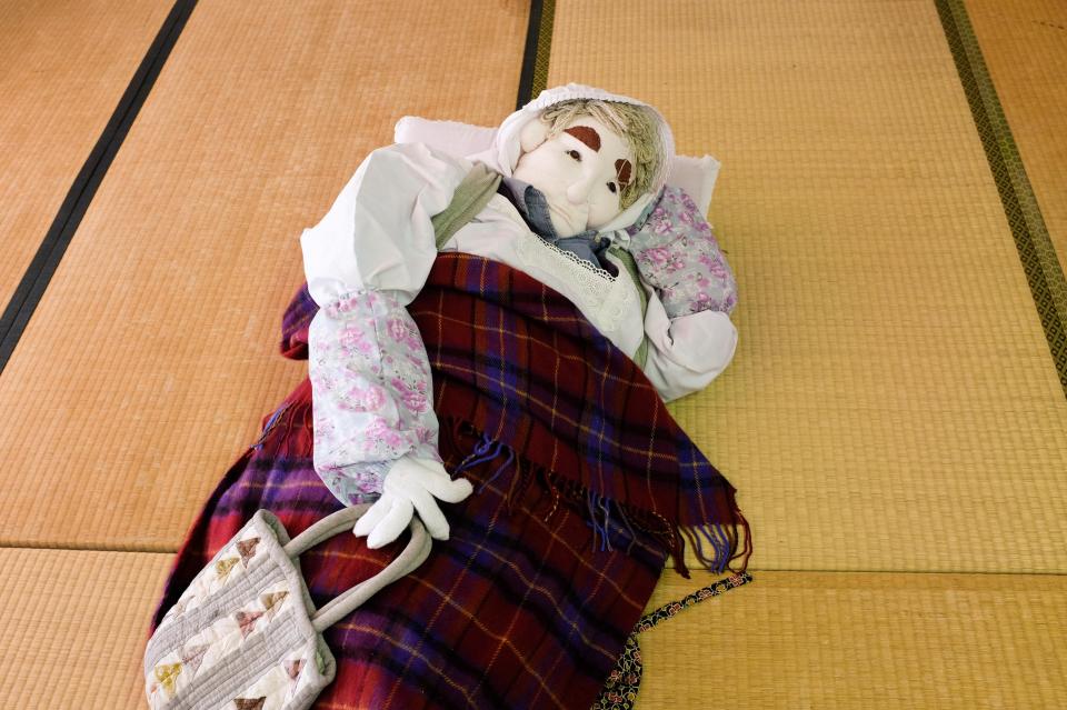  A doll resembling an elderly woman lies on the floor of a home in the gradually shrinking village