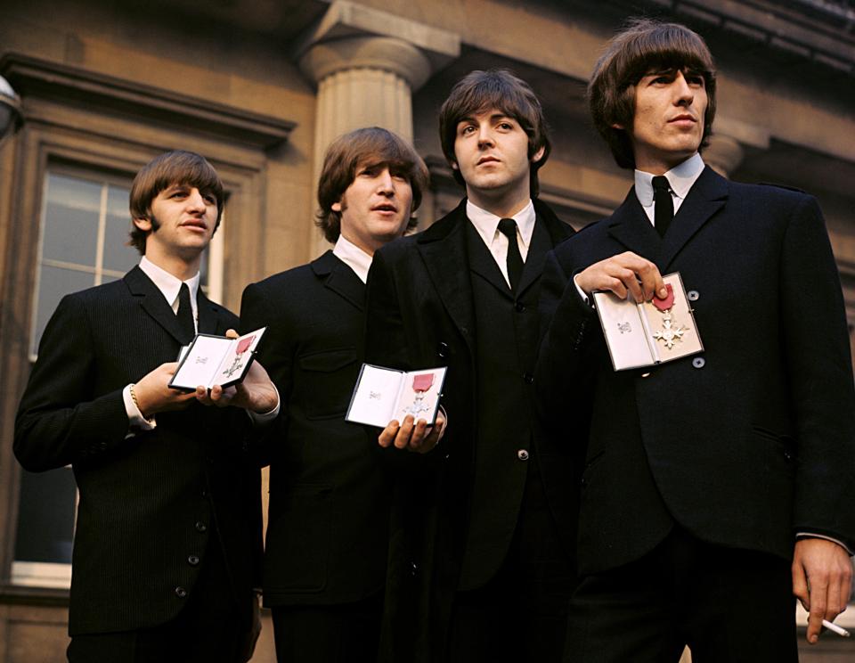 The Beatles showing their MBE insignias in 1965 after receiving them from the Queen