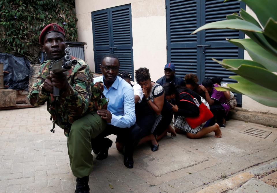 Terrified survivors are cowering for safety behind a member of the security forces