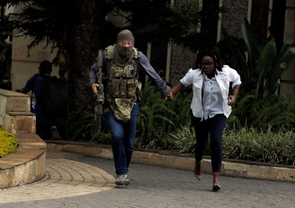 The balaclava-clad troop escorts another bystander to safety