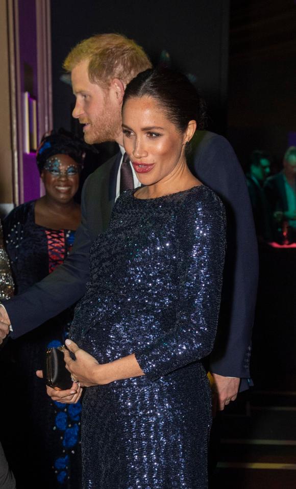  Meghan Markle put a protective arm around her baby bump