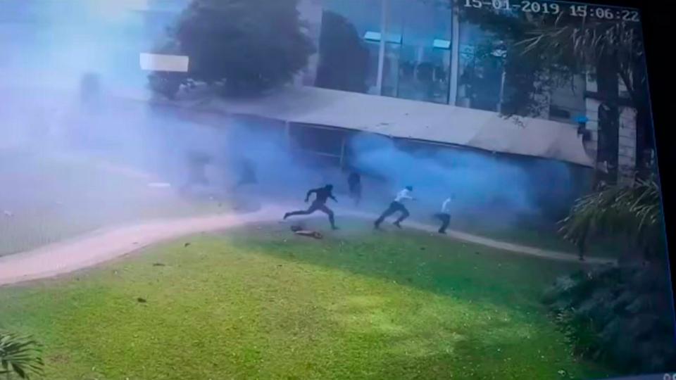 In this image made from security camera video footage, people run after a man blew himself up in a grassy area at the DusitD2 leisure complex