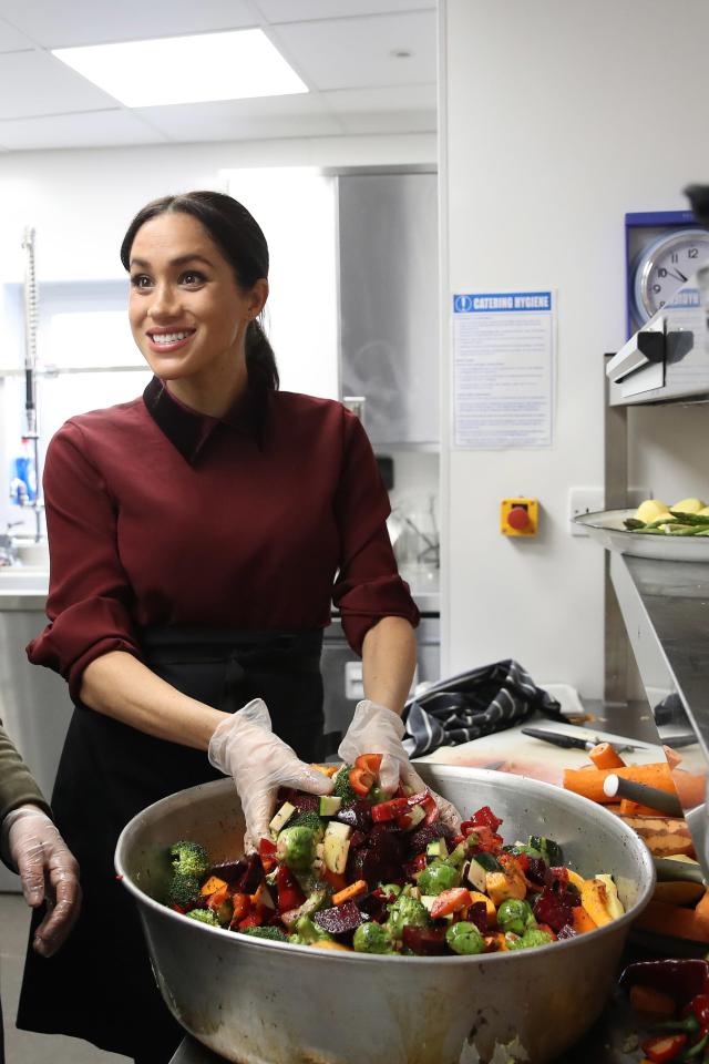 Meghan Markle preparing vegetables in a kitchen.