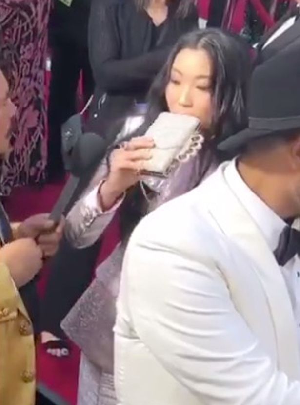  US rapper Awkwafina takes a swig of tequila from a flash disguised as a bag