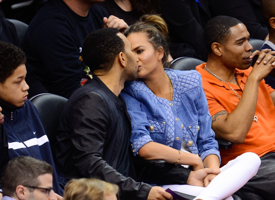  Chrissy Teigen looks at John Legend when he plants a kiss on her lips at a basketball game in 2014