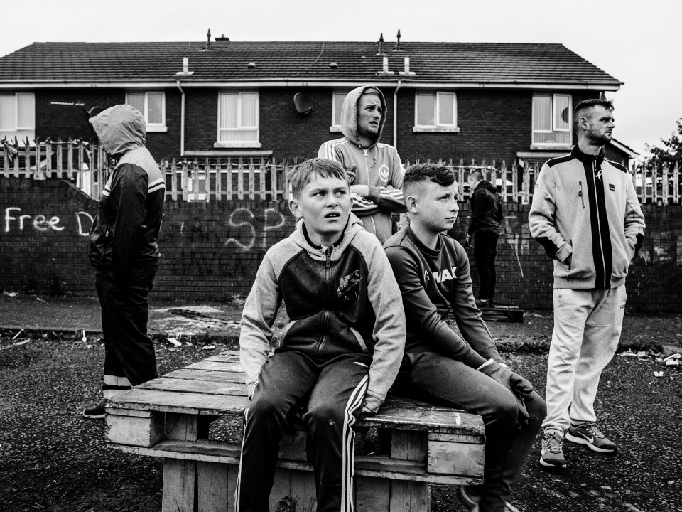  Something or someone has caught the attention of these young boys as they sit on pallets outside a housing estate