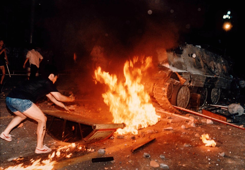 A student protester puts barricades in the path of an already burning armoured personnel carrier