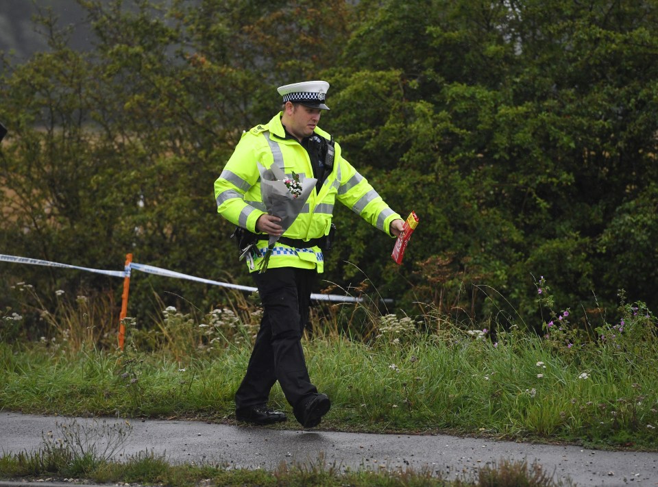  A police officer lays flowers at the scene