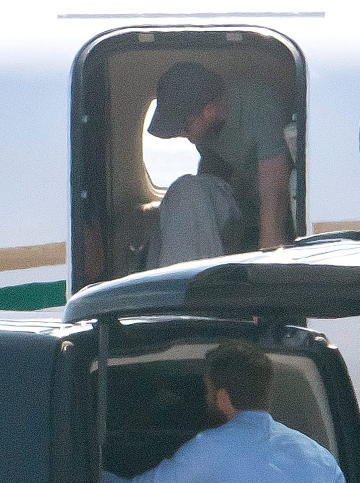 Prince Harry with his cap and shades on as he leaves the private jet