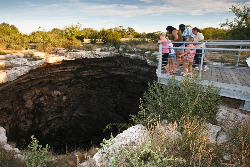 Tourists look down into Devil's Sinkhole.