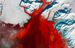 Red and black seem to mar the icy glacial landscape of southern Iceland. The grey-black filaments are past glacial melting outbursts called jökulhlaups. These abrupt flooding events gush down this outwash plain called Skeiðarársandur, one of the world’s largest. The Skeiðarárjökull Glacier reaches down from the top left of the image. The plain is mostly devoid of vegetation, but red colouring indicates low moss, birch shrub, and other grass species.