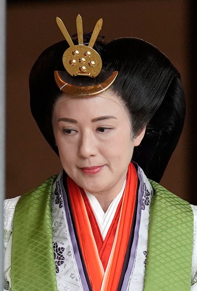  Japanese Empress Masako wearing heavy robes and with hair flowing down her back, stood in front of a smaller throne to the side