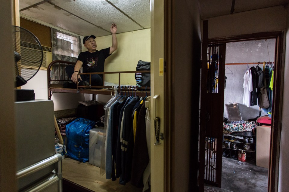  This picture shows David Yu touching the ceiling as he sits on his bed in his 'cubicle' flat, built which he shares with other tenants on the roof of a ten-storey residential building in the Kowloon district of Hong Kong