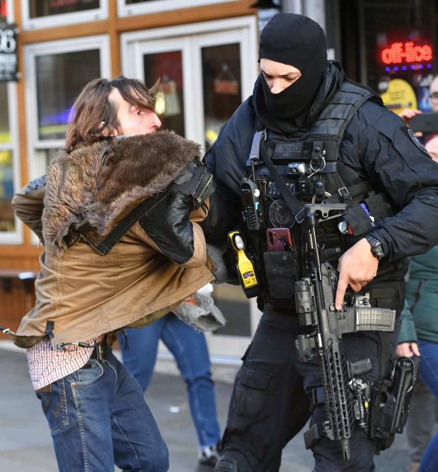 A police officer moves an uninvolved person away from a cordon on London Bridge