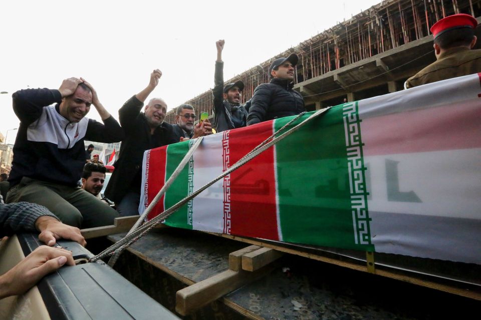 Iraqis mourn over the military leader's coffin during this morning's funeral process 