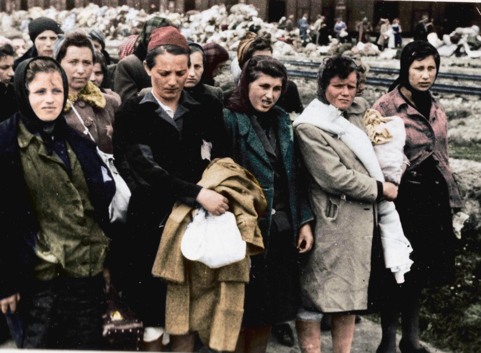  A group of Jewish women selected for slave labour, with the discarded belongings of those sent straight to their deaths piled up in the background