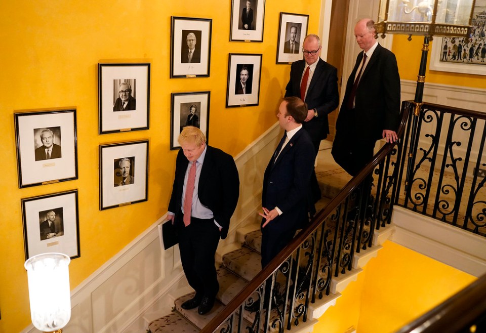 Boris Johnson, Matt Hancock and Chief Medical Officer Chris Whitty walk down the stairs together after press conference on the coronavirus on March 12